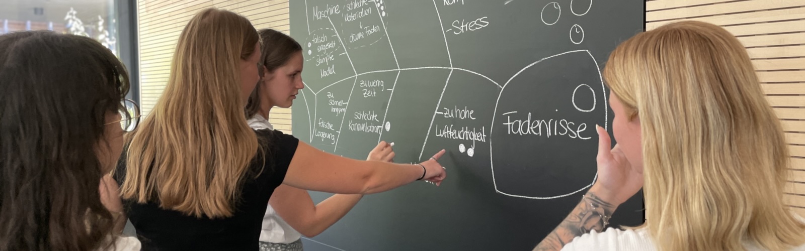 4 Schülerinnen stehen an einer Tafel